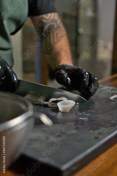 Obraz Chef Expertly Slicing Fresh Squid on Cutting Board in Commercial Kitchen