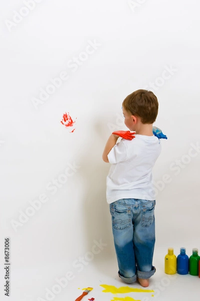 Fototapeta Child making hand prints on the wall with paint