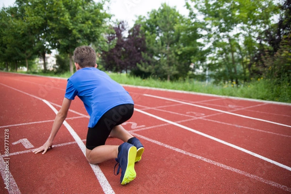 Obraz The athlete stands on the starting line on the track.