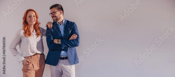 Obraz Business partners posing in front of gray background, looking at camera and smiling.