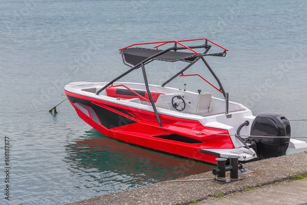 Fototapeta Moored red-white-black motorboat on the background of the sea