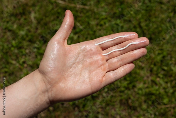 Fototapeta A man applying the correct amount of sunscreen for face and neck (two finger lengths).