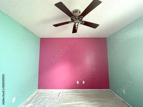Obraz A brightly painted bedroom with pink and teal colored walls. The floor is covered with drop cloths so the room can be repainted.