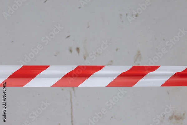 Fototapeta A red and white striped tape is on a wall