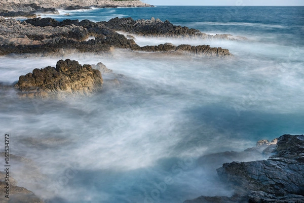 Obraz Long exposure shoot of sea waves crashing on seashore and rocks seascape.