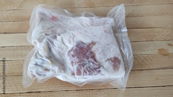 Obraz Piece of frozen pork lard in a vacuum packaging on the wooden background