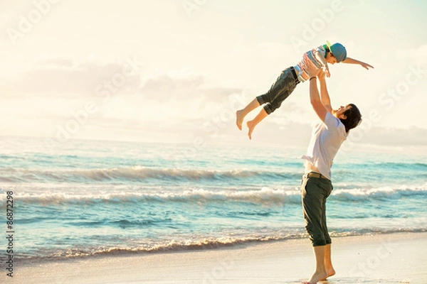 Fototapeta Father and son having fun together in sunset ocean on summer
