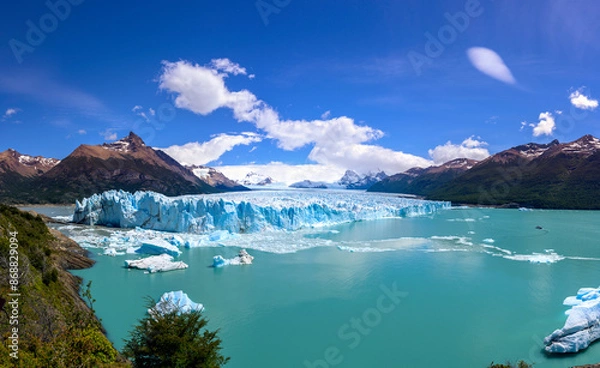 Fototapeta Perito Moreno Glacier high resolution panorama. A large tourist boat on the far right appears miniscule and gives a sense of scale of the glacier height of 74 m (240 ft) above the surface of the water