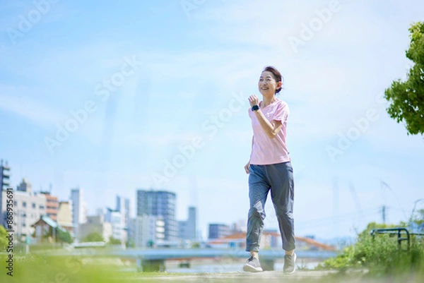 Fototapeta 春の新緑の中ランニングを楽しむスポーツウェアをきたシニア女性