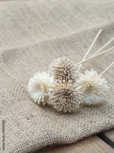 Fototapeta Dry flowers on burlap hessian sacking on the wooden table.