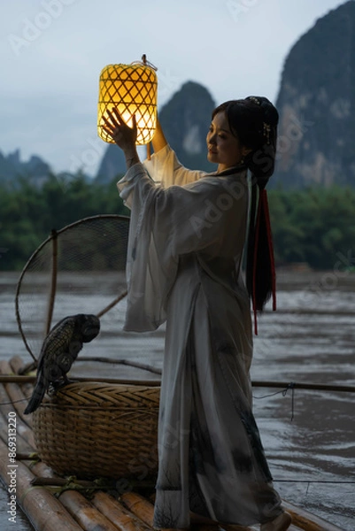 Obraz Hanfu Girl holding a lantern on a bamboo raft, Xingping, China. Vertical