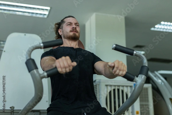 Fototapeta Man workout on pressing machine in gym calories burn lose weight for health. Strong sportsman exercising chest press machine in gym. Exercise to increase arm and shoulder muscles.