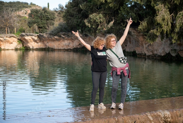 Fototapeta three middle-aged sisters posing by a lake after a hike