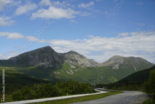 Fototapeta  Mountains and nature of Norway. Summer and sunny day. Green valley and white clouds. Blue sky. Snow on the slopes of the mountains.
