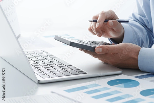 Fototapeta Accounting calculation. Calculating tax with calculator and laptop. Filing and paying taxes.