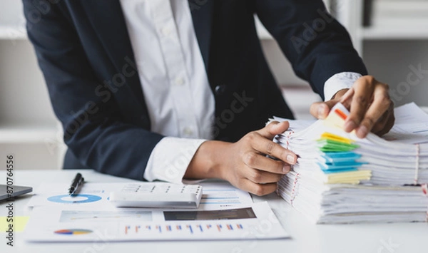 Fototapeta Businesswoman hands working on stacks of paper files for searching and checking unfinished document achieves on folders papers at busy work desk office.
