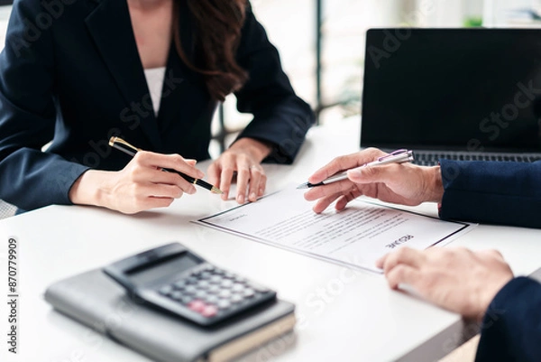 Fototapeta Two people are sitting at a table with a piece of paper in front of them