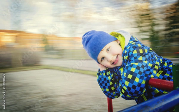 Fototapeta Boy posing on the carousel in motion.