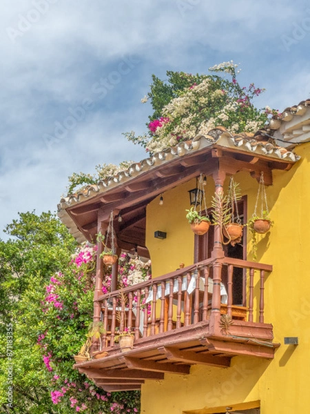 Fototapeta Beautiful yellow buildings with colorful flowers and bougainvillea in colonial area of Cuba.