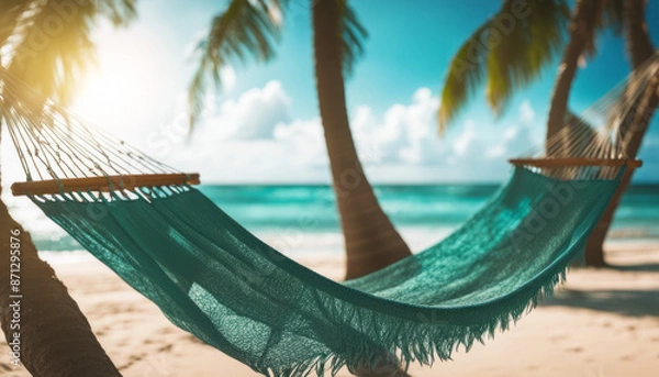 Fototapeta Low-angle shot of a hammock swaying gently between two palm trees on a tropical beach, overlooking the turquoise ocean.