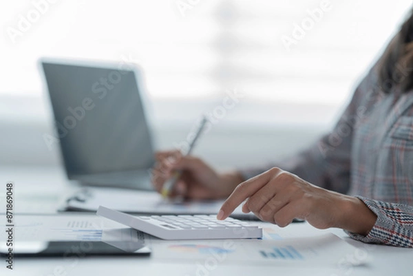 Obraz A photograph of a woman's hand using a pen and calculator to work.