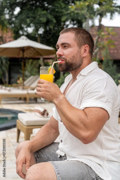 Obraz man drinking juice by the pool
