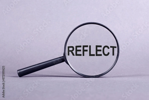 Fototapeta A magnifying glass displaying the word reflect in clear text, emphasizing introspection and self-examination.