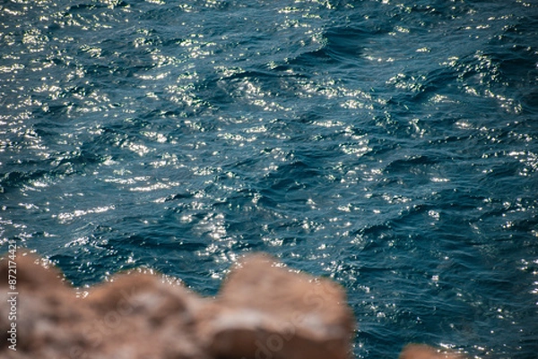 Fototapeta Close up of the blue waves and the rocks of the cliff