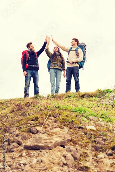 Fototapeta group of smiling friends with backpacks hiking