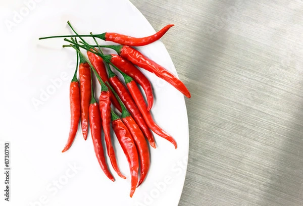 Obraz Hot Red Cayenne Peppers na białym talerzu na blacie ze stali nierdzewnej