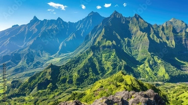 Fototapeta A breathtaking view of a mountain range with sharp peaks and lush green valleys, under a clear, blue sky.