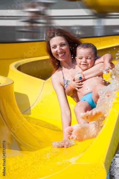 Fototapeta child and mom playing with the slide in the pool