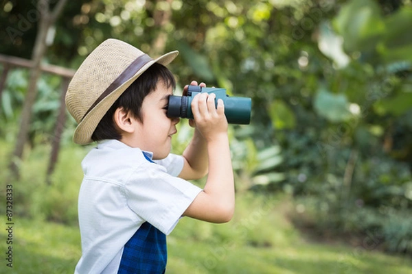 Obraz Little asian boy looking trough a binoculars with smiling face i
