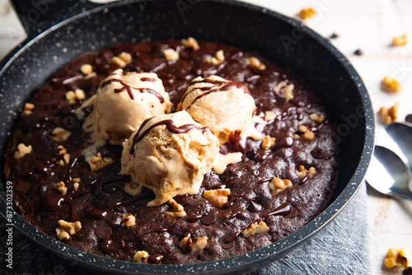 Fototapeta Homemade brownie cooked in a skillet, not baked, with melting vanilla ice cream scoops
