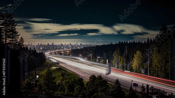Obraz night time view of a highway with a city in the distance