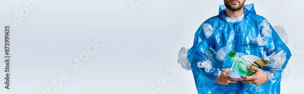Fototapeta A man stands against a white backdrop, enveloped in a sea of plastic.