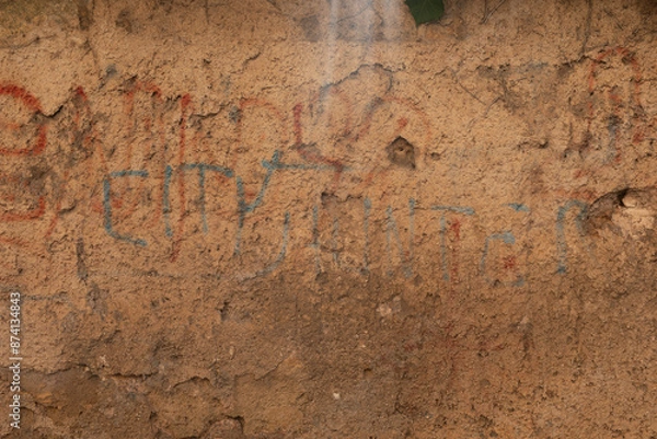 Fototapeta A weathered wall with faded writing in red and blue