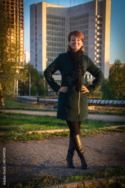 Obraz Young beautiful woman in a park at sunset on a background of hig