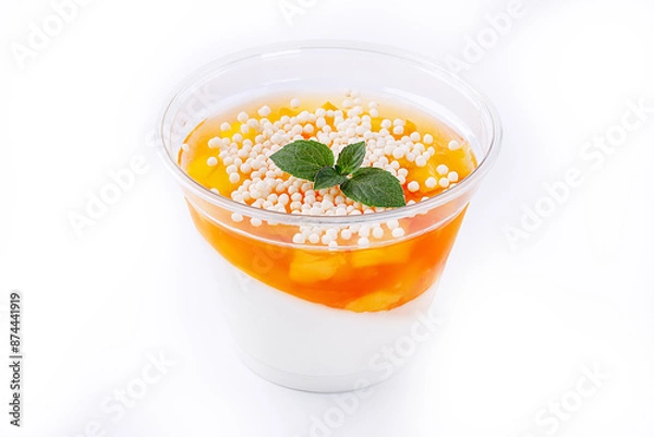 Obraz Orange panna cotta with mango slices in a glass on a white ilolate background