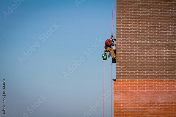 Fototapeta Steeplejack Builder worker plastering industrial building facade