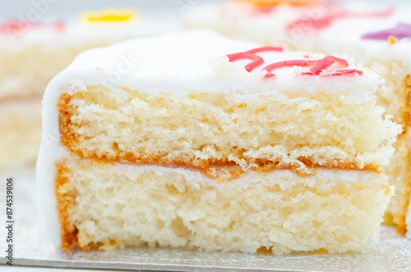 Fototapeta A slice of white cake with color frosting on top