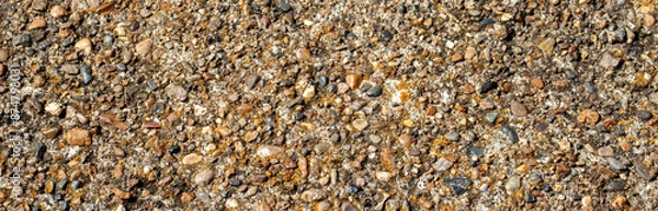 Fototapeta Large and small pebbles on the surface of concrete, top view. Various-sized pebbles, flat layout. Pebbles of different sizes lie chaotically.