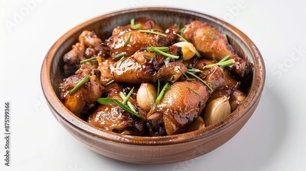 Fototapeta A dish of Filipino adobo with chicken and garlic on a white background.