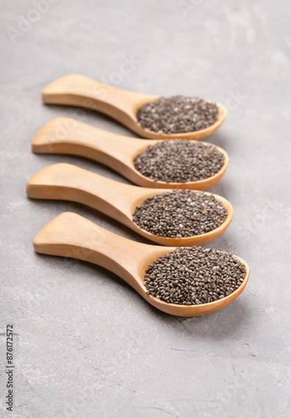 Fototapeta Four wooden spoons full of chia seeds close-up on concrete background