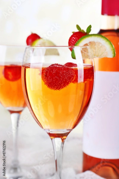 Fototapeta Glasses of wine with strawberries and slice of lime on light background