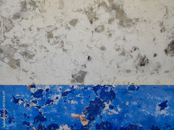 Fototapeta Close-up of an old wall with weathered paint and peeling layers. White and blue old wall with peeling paint