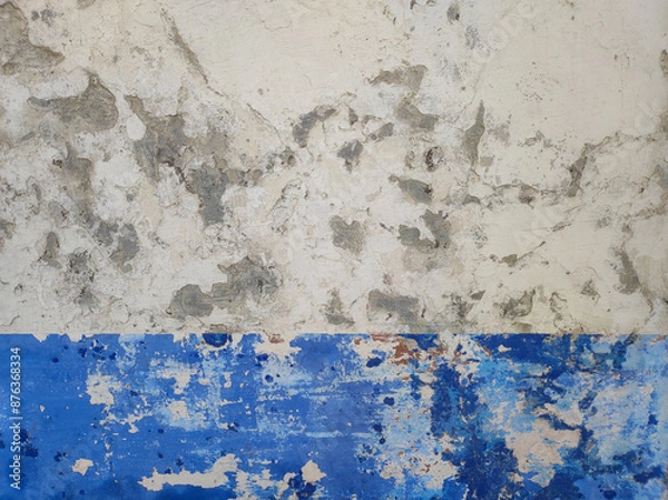 Fototapeta Close-up of an old wall with weathered paint and peeling layers. White and blue old wall with peeling paint