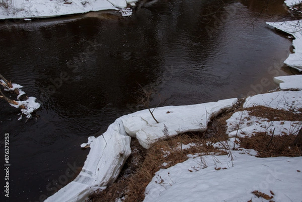 Obraz a wide dark river in spring, with a lot of snow on its banks