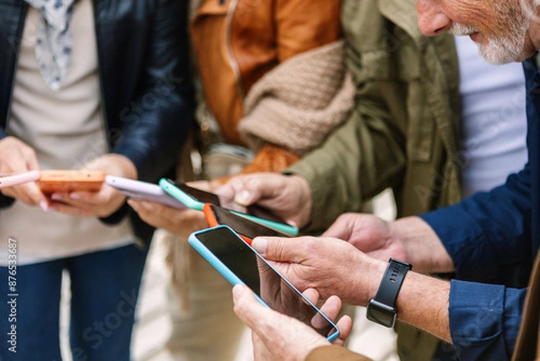 Fototapeta Close up view of senior group of people using mobile phone at city street. Elderly people connected online browsing internet on smart phone device. Technology and elderly lifestyle concept.