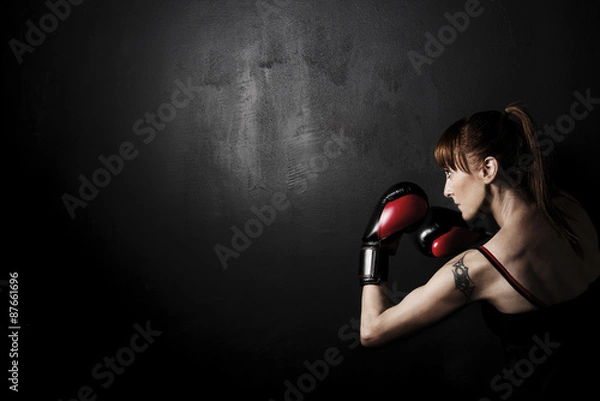 Fototapeta Woman Boxer with Red Gloves on Black Background, high contrast with desaturated grunge filter in studio
